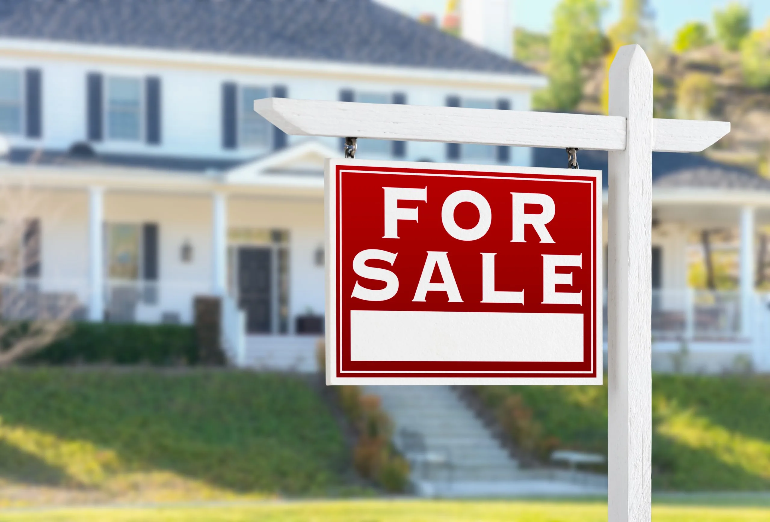 A bright red "For Sale" sign stands in front of a house