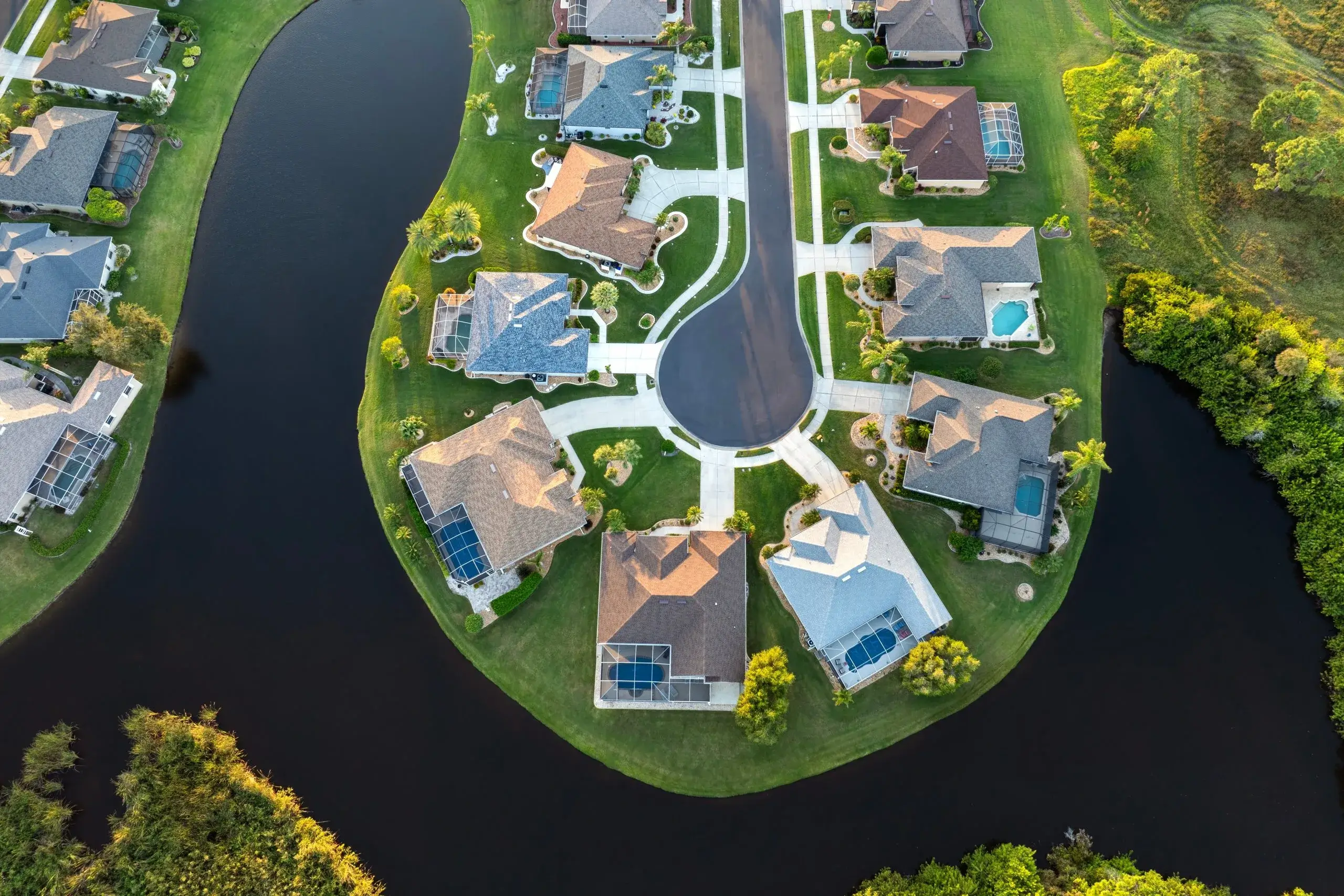 Aerial view reveals a curved street lined with houses beside winding waterways
